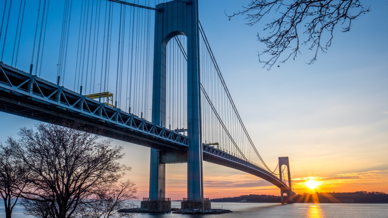 The Verrazzano-Narrows Bridge is shown at sunset connecting Brooklyn to Staten Island in New York City.