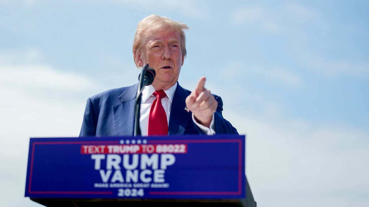 Former President Donald Trump pointing his finger behind a Trump - Vance campaign lectern