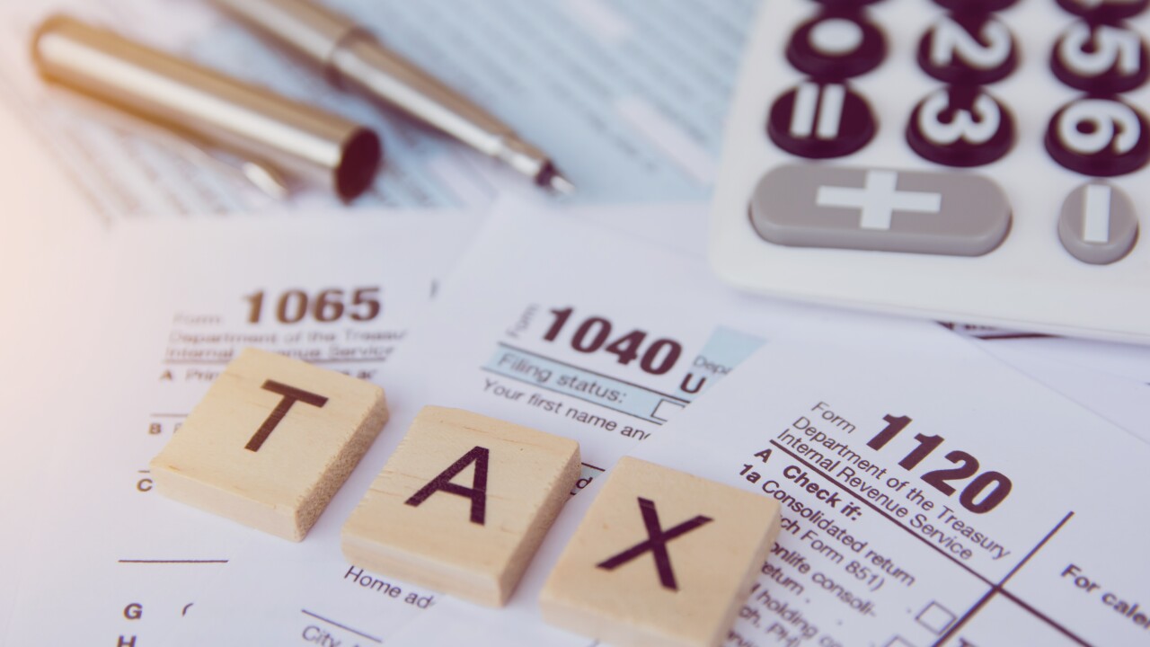 Tax season with wooden alphabet blocks, calculator, pen on 1040, 1065, 1120 tax form backgrounds